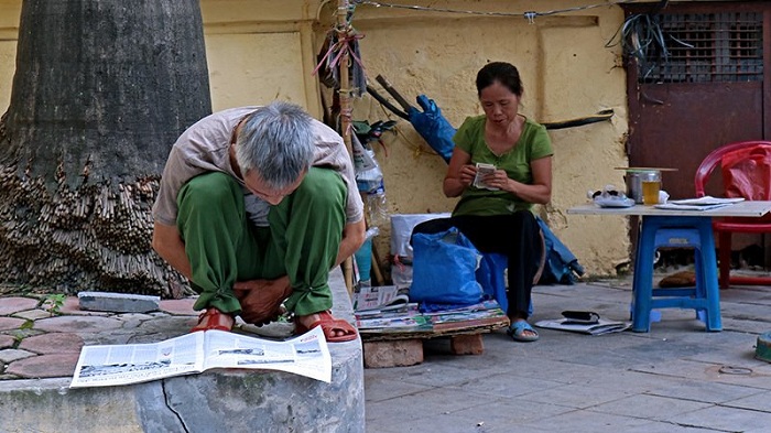 visit hanoi in early morning reading newspaper